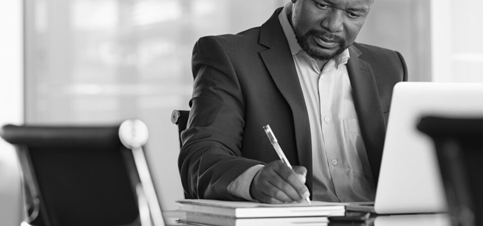 SINGLE-IMAGE_man-with-pen-and-books-at-desk_feb24
