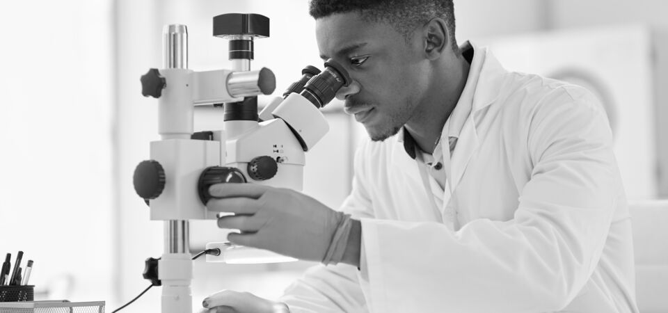 SINGLE-IMAGE_scientist-looking-at-test-samples-through-a-microscope_mar25